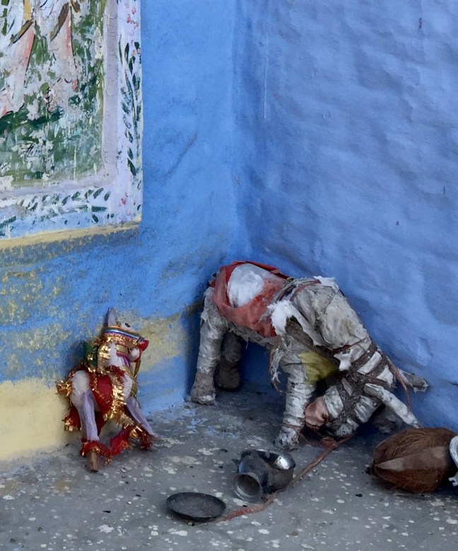 Two elephants at a little make-shift temple on a deserted path. 